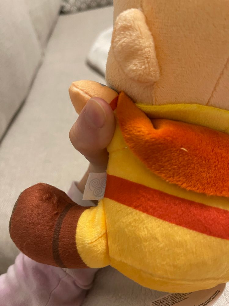 Aang plushie has a tag with an airbending symbol on his side.