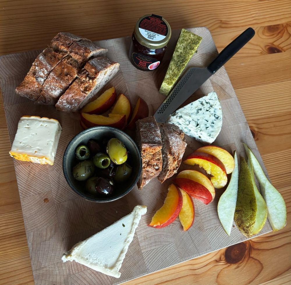 Bild einer Köseplatte mit Heumilchkäse, Gorgonzola, Walnussbaguette, Birne, Nektarine, Perignon, und Romadur, Oliven und Feigensenf.