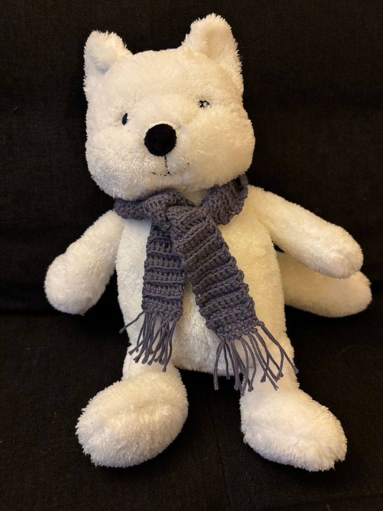 Bild von einem weißen Polarfuchsstofftier mit einem rauchblauen Häkelschal um den Hals.