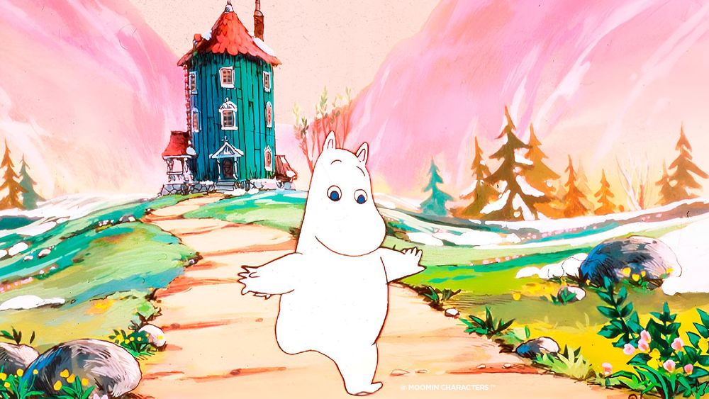 A still from the show Moomin, with the main character Moomin running down the path away from the blue Moomin house, with some pink mountains in the background.