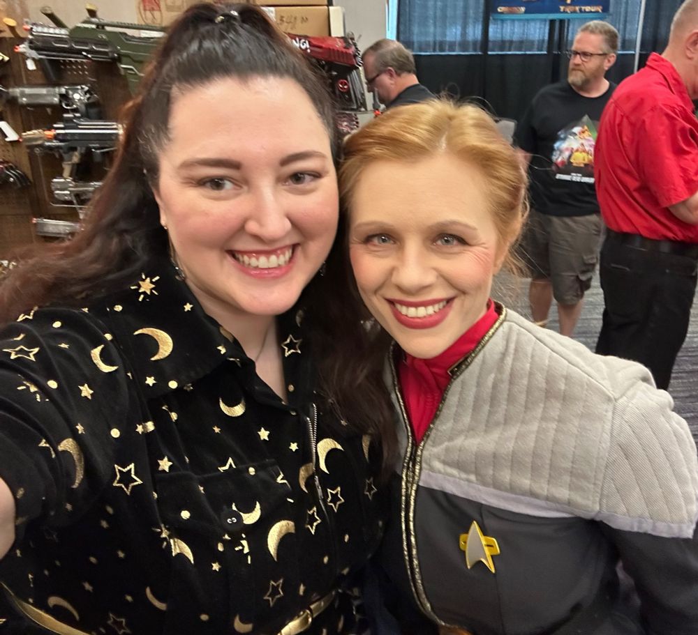 Amy in a black jumpsuit with gold moons and stars and Rebecca in her Janeway uniform