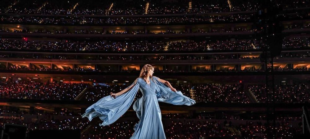 Taylor Swift dancing in a flowing blue dress while singing 