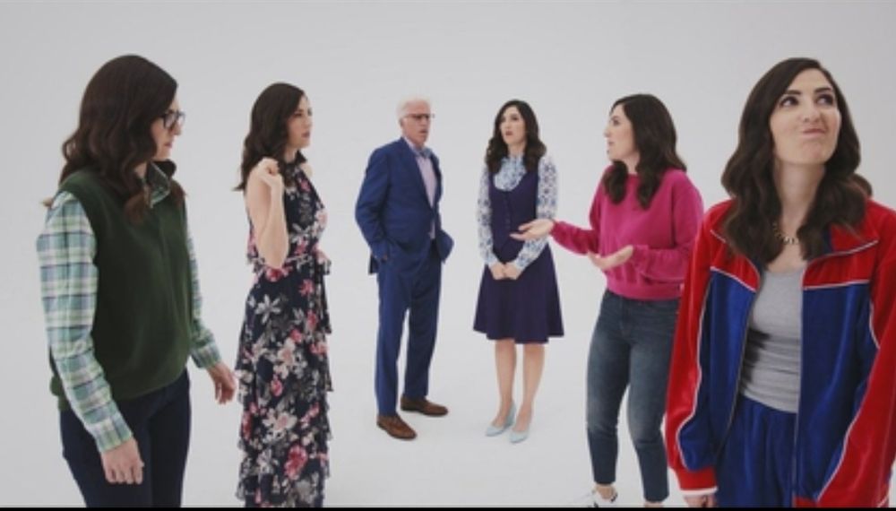 Still from The Good Place S3E10 with Ted Danson and 5 D'Arcy Cardens in different outfits characteristic of characters Jason, Chidi, Eleanor,  Tahani, and Janet, against a pure white background representing Janet's void.