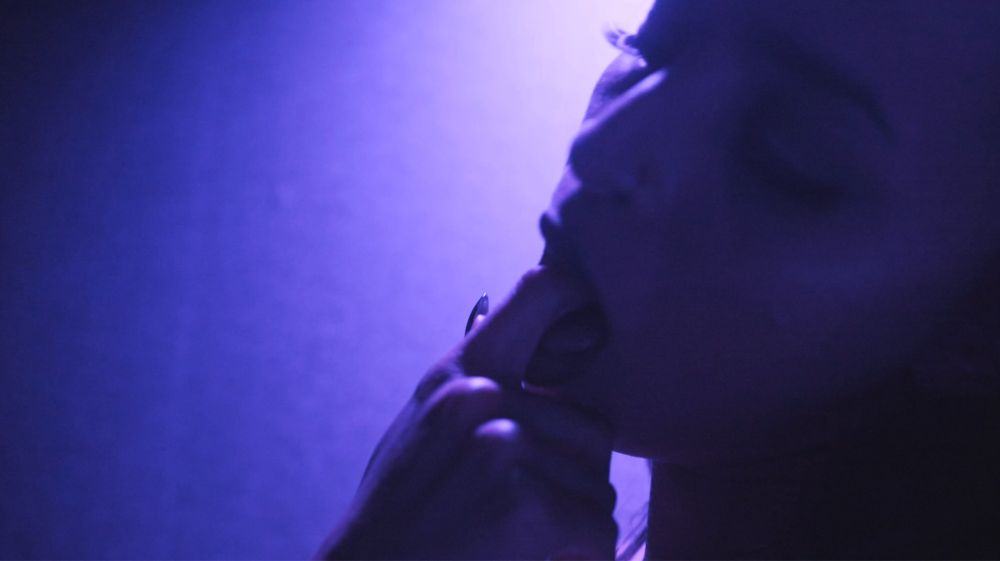 Screenshots from XXX production company trailer. Title card, redhead posing, finger in mouth, woman in pleasure.