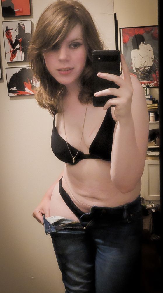 a mirror selfie of Diletta;
a brunette woman with side swept bangs and collarbone length hair
she's wearing black underwear and is pulling down a pair of dark blue denim jeans, exposing one hip
a necklace dangles between her cleavage 