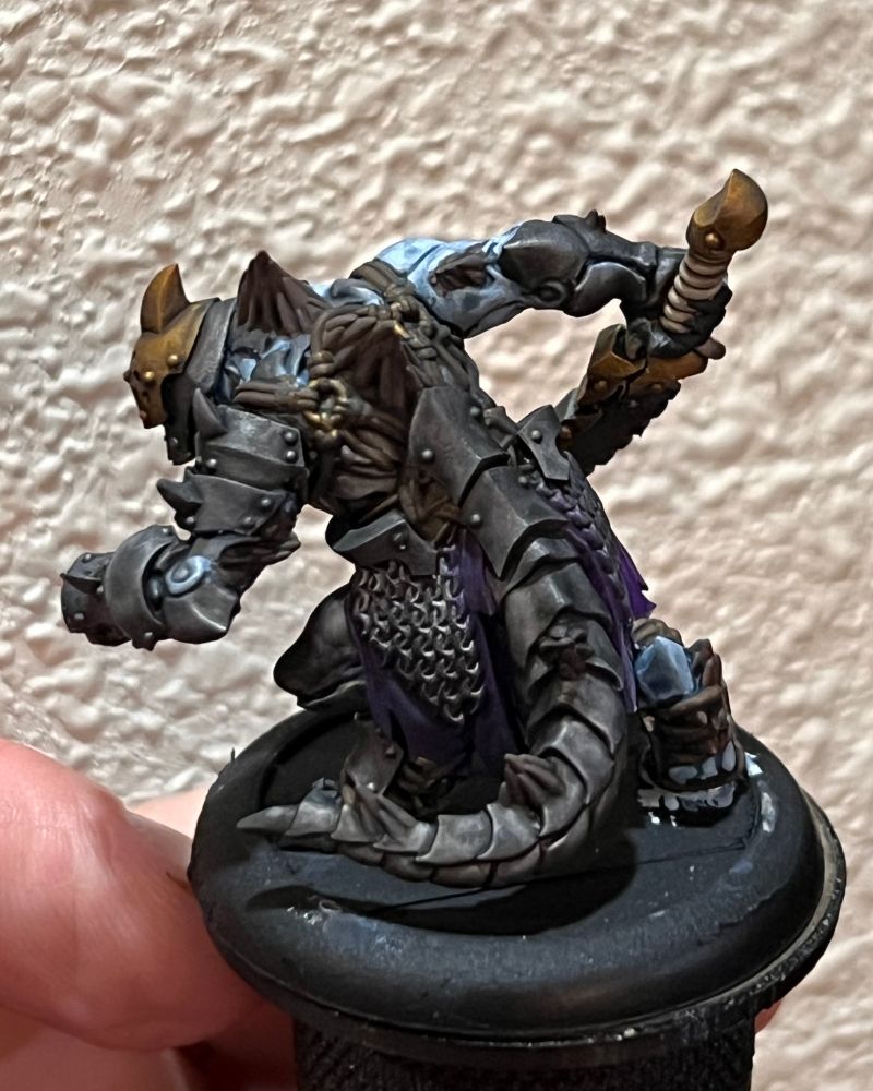 A rear view of a Khymaera model from Warmachine Mk 4. This shot allows a better view of the numerous layered armor plates covering his back and tail, as well as the spines growing out of the skin.
