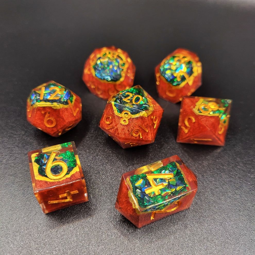 Handmade resin geode dice set with druid brown bases and green iridescent glitter inside. Numbers are inked with gold paint.