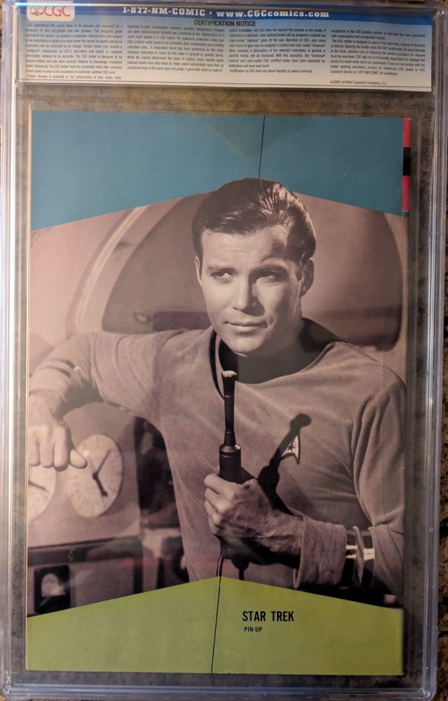 A rear cover picture of Star Trek Gold Key #1 published October 1967. It is encased in a CGC case graded 8.0. It has a black and white photo of Captain James T Kirk holding a futuristic device that looks somewhat like a skinny microphone.