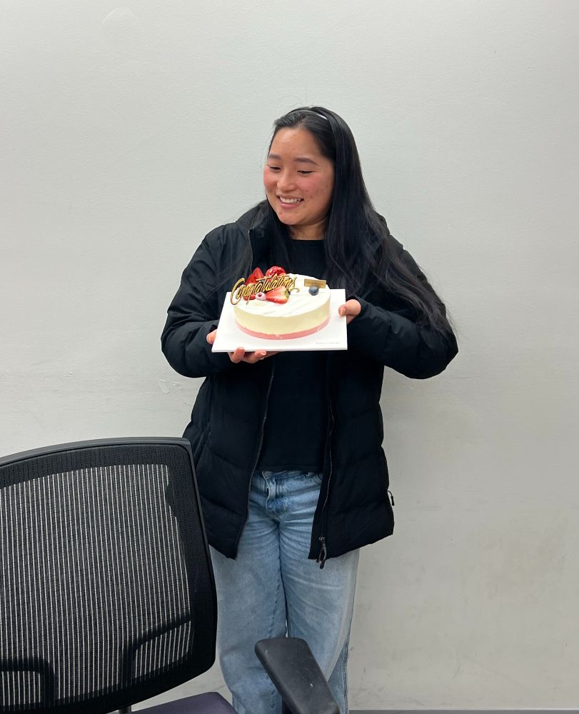 Fia holding a cake with a sign that says congratulations