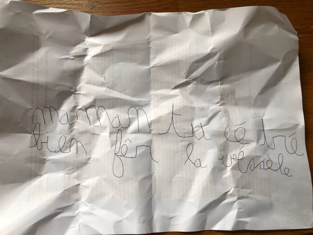 Une feuille blanche avec une écriture d’enfant : « maman tu cé tré bien fêr la véssèle »