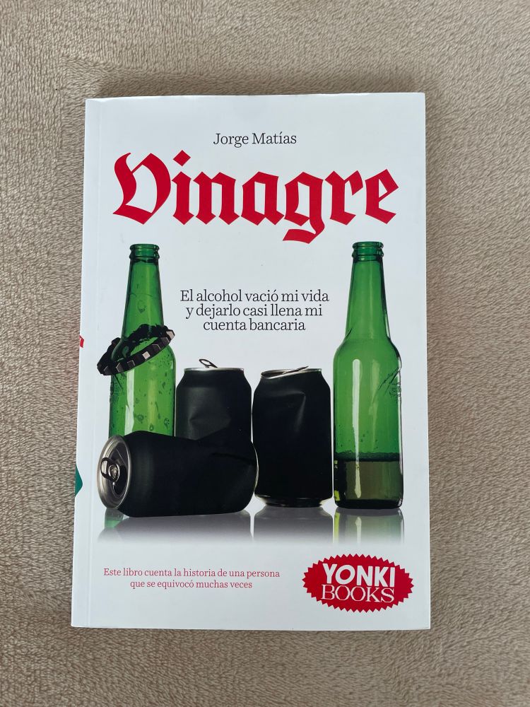 Portada de "Vinagre" de Jorge Matías. Portada blanca con 3 latas y 2 botellines de cerveza vacíos colocados de forma artística (1 lata tumbada en un primer plano, botellines en segundo plano a los costados y las 2 latas restantes en segundo plano entre ambos botellines)