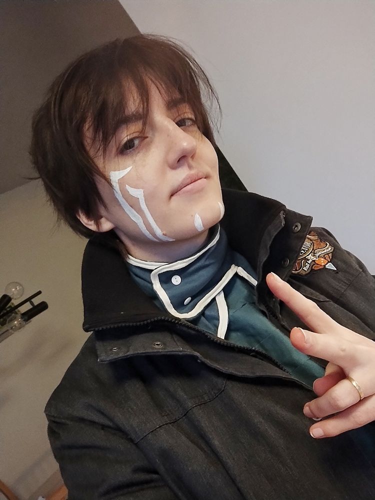A picture of a person dressed up as Jace Beleren from magic the gathering, they are wearing a normal real life human winter coat over the Jace cosplay top, no cloak in sight. 
