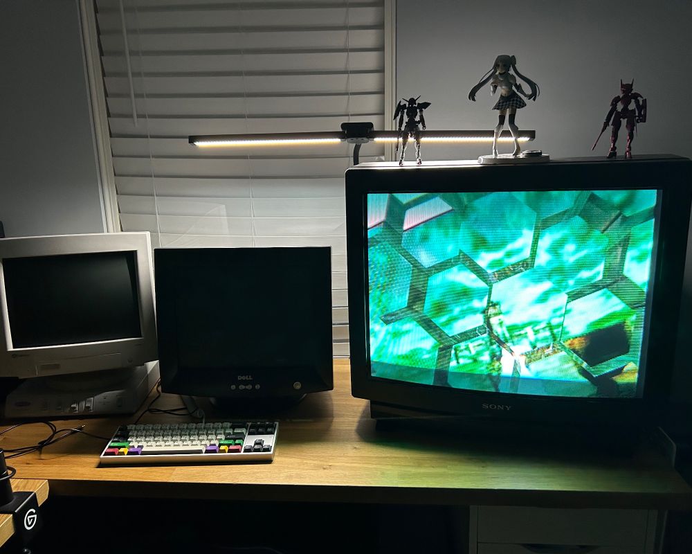 a desk with 2 CRT monitors and a CRT TV