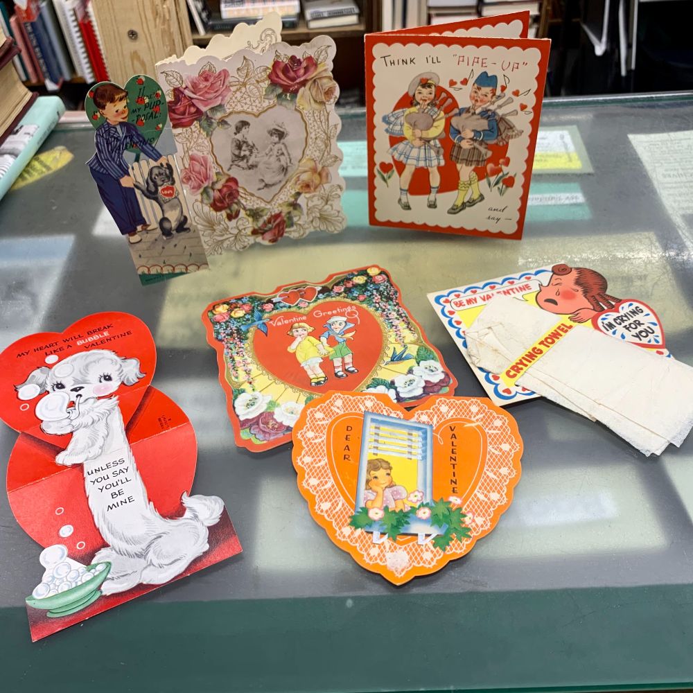 A display of vintage Valentine's Day cards laid out on the table. All of the cards feature Victorian era and cherub-like artwork.