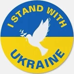 Circular logo blue on top half, yellow on bottom half. Peace dove in white in the center. Words "I stand with Ukraine" written around the edge.