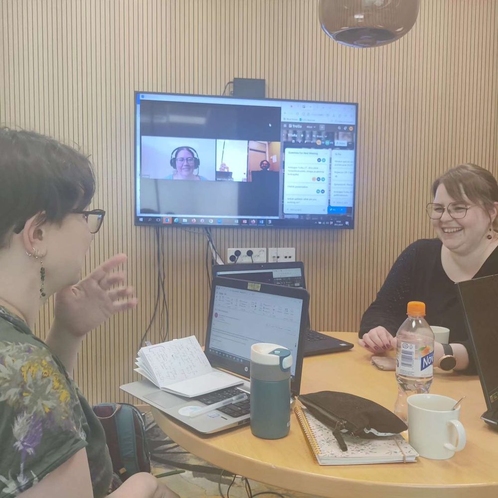 Photo of some TiTaRa team members at a meeting. One is on Zoom, two others in the room. Everyone's laughing.