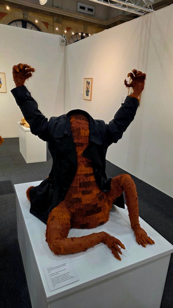 A large furry headless creature wearing a jacket with it's arms up.