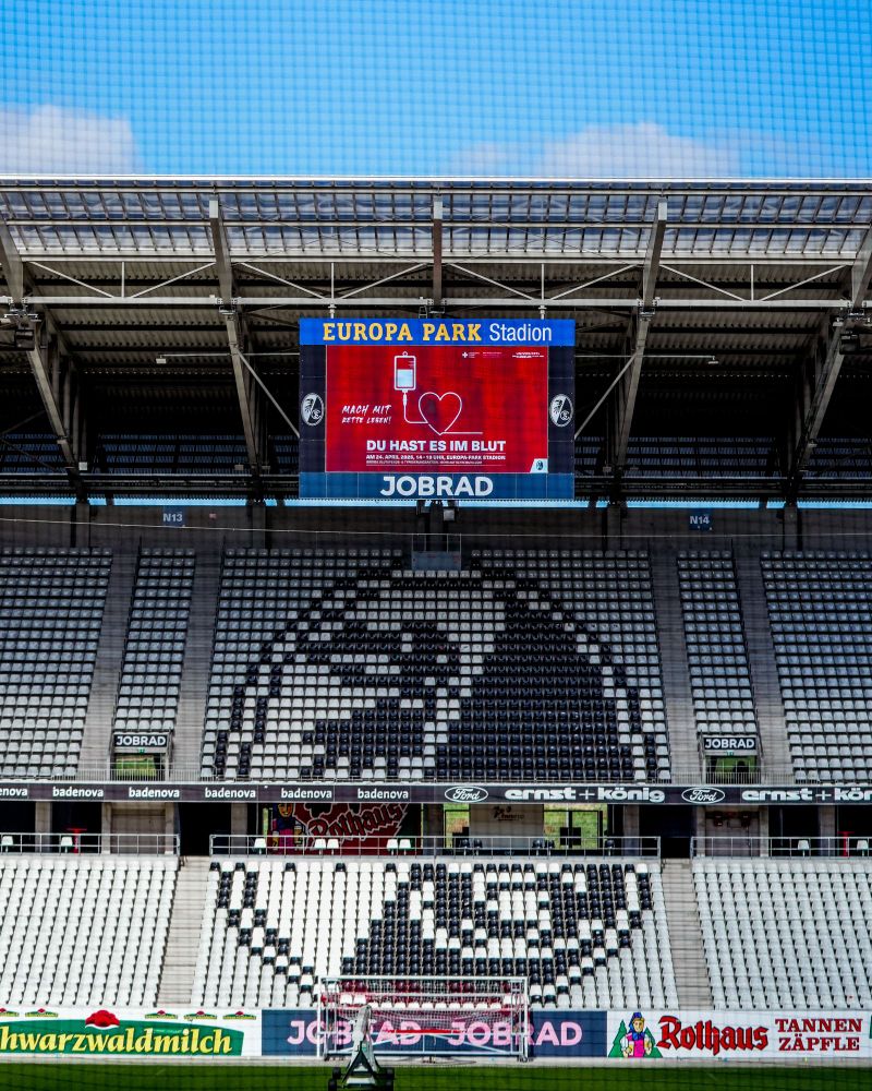 Nordtribüne im Europa-Park Stadion. Auf der Anzeigetafel ist die Grafik zur Blutspendeaktion mit dem Slogan "Du hast es im Blut" zu sehen.