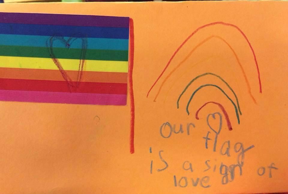 Child’s art with rainbow flag and “our flag is a sign of love” written in crayon 