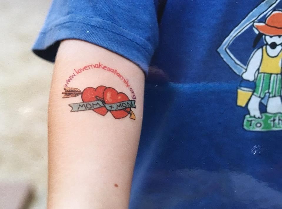Child’s arm with temporary tattoo that says “Mom and Mom.”