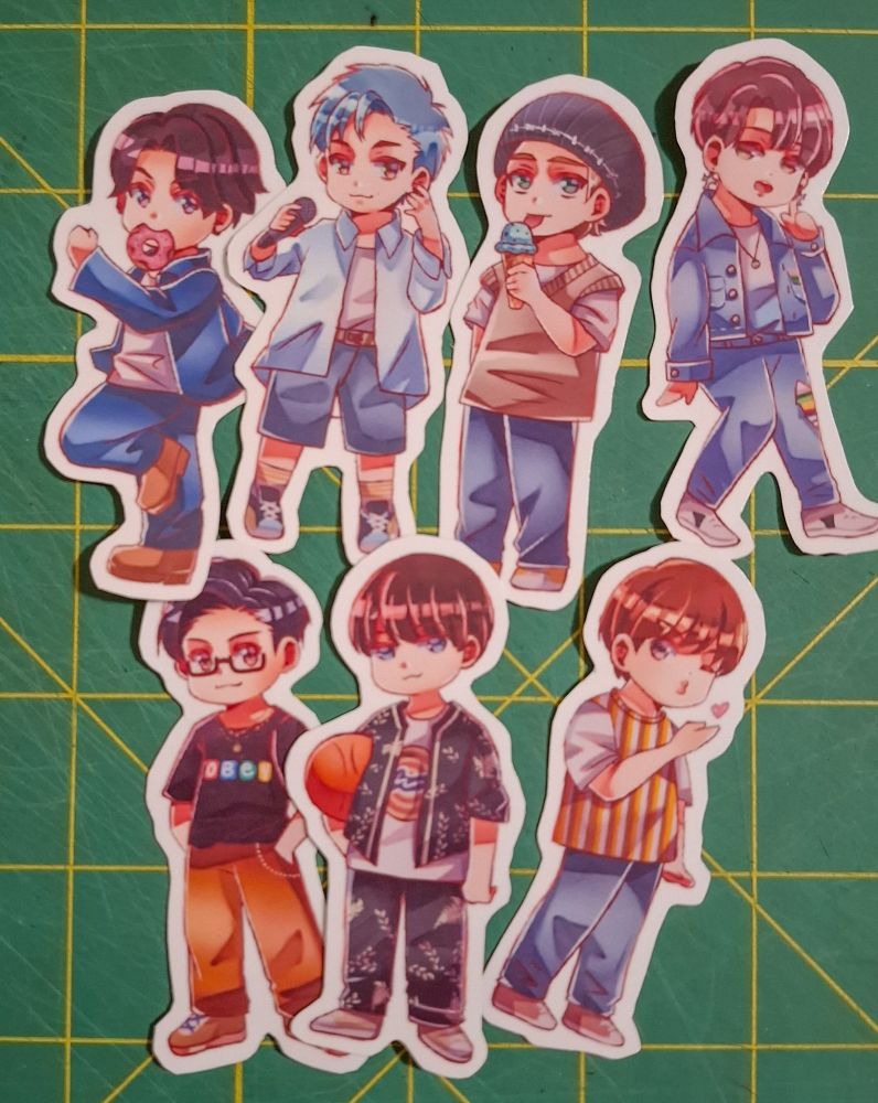 bts dynamite chibi stickers on a green cutting mat