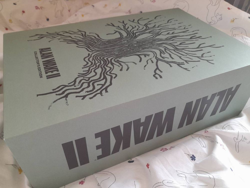 The huge olive slipcase for the Alan Wake 2 Collector's Edition, with an image of a tree made up of waving lines.