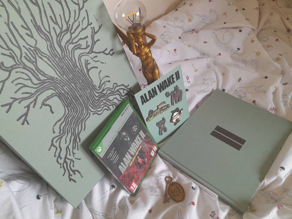 The Alan Wake 2 Collector's Edition with golden Angel Lamp. Coffee World Pins, the Room 665 keyring, Xbox Deluxe Edition, and Artbook.