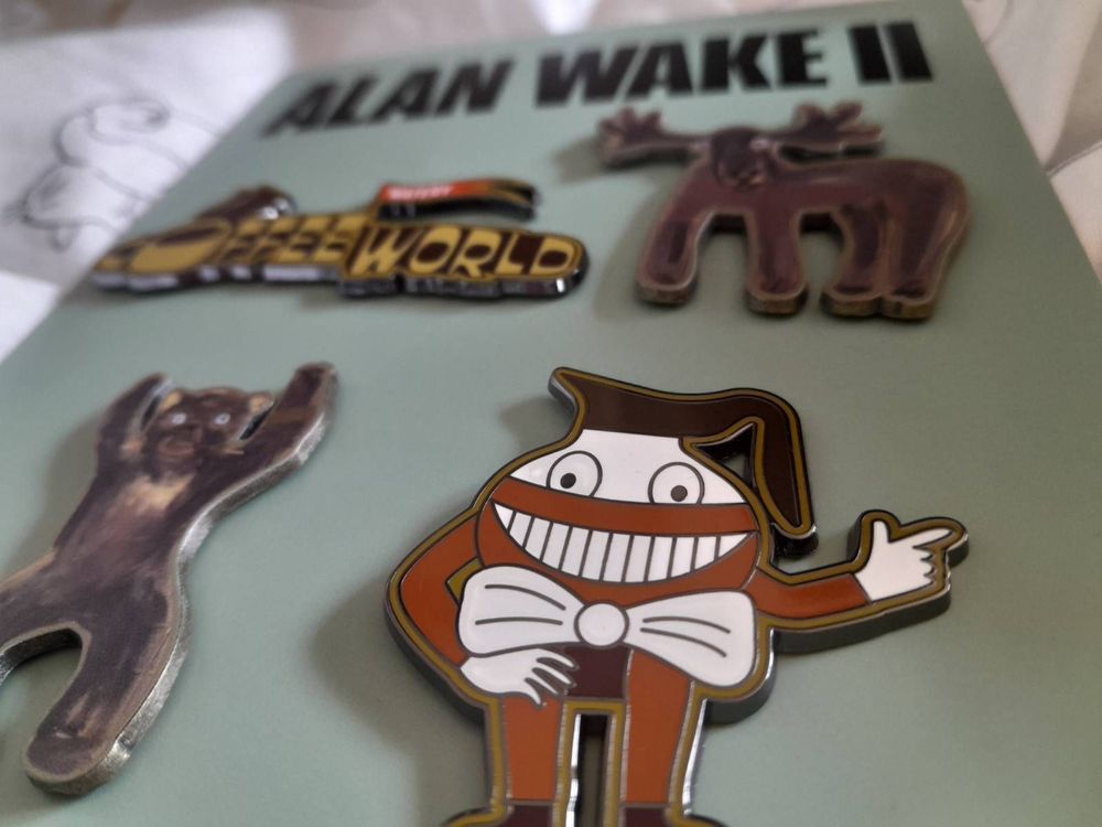 A close up of the Coffee World pins. In the forefront is the grinning coffee pot mascot surrounded by cardboard designs of a moose and a bear.