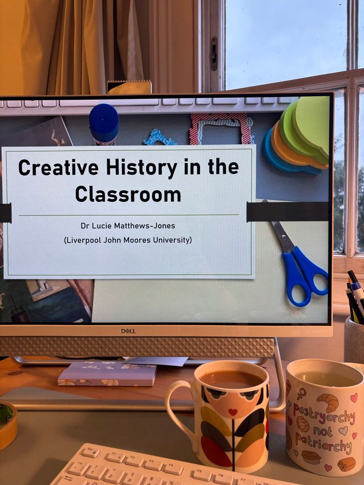 A computer screen with a PowerPoint slide of craft stuff and text that reads: 

Creative History in the Classroom
Dr Lucie Matthews-Jones
(Liverpool John Moores University)

Mugs at the front. 