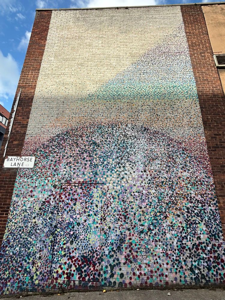 Multi coloured dots on a wall with a street sign 