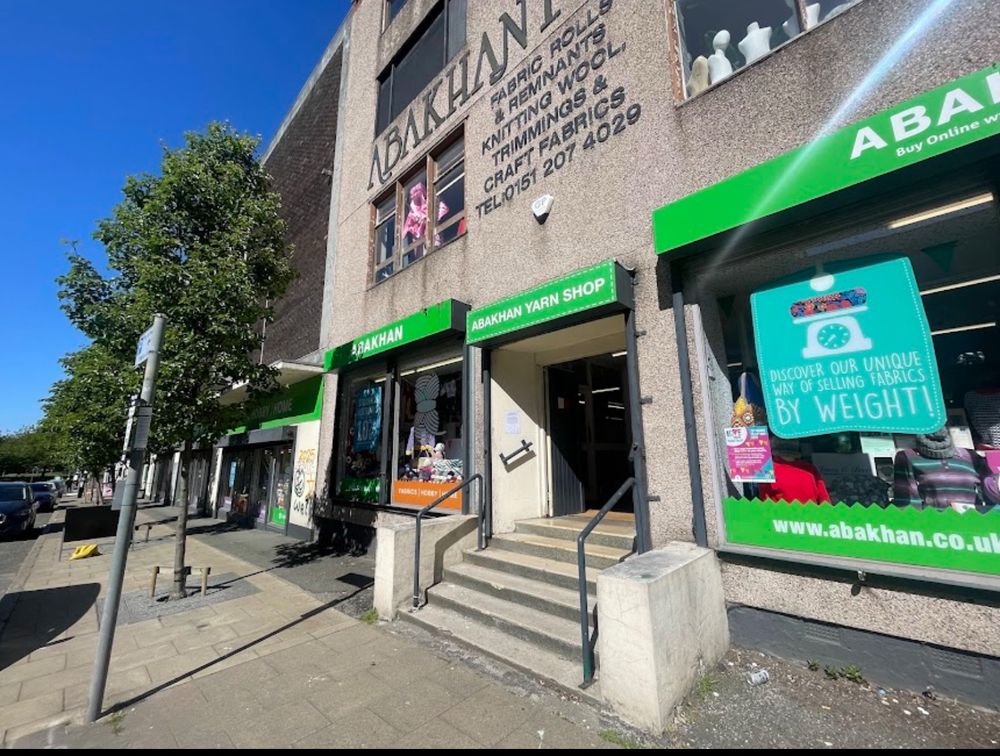 A grey shop front with green shop signs 