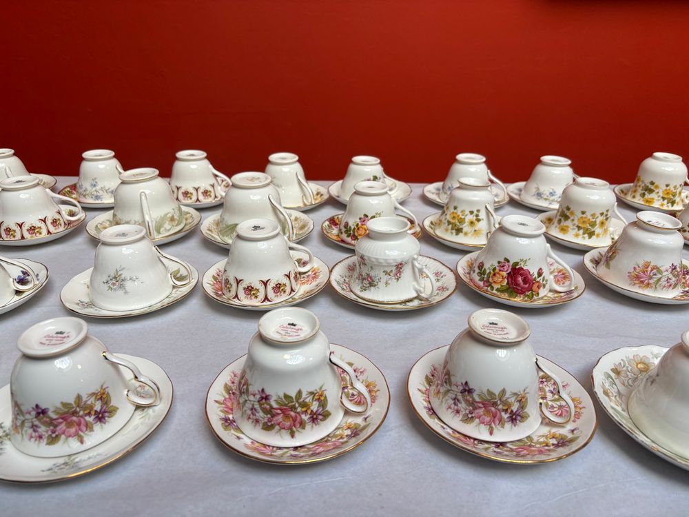 A table of tea chows with ornate flowers on a white table cloth and a red wall behind 