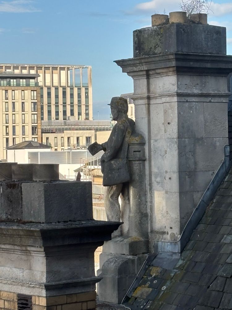 Look onto a statue or a postman holding out a kettle with building in the distance 