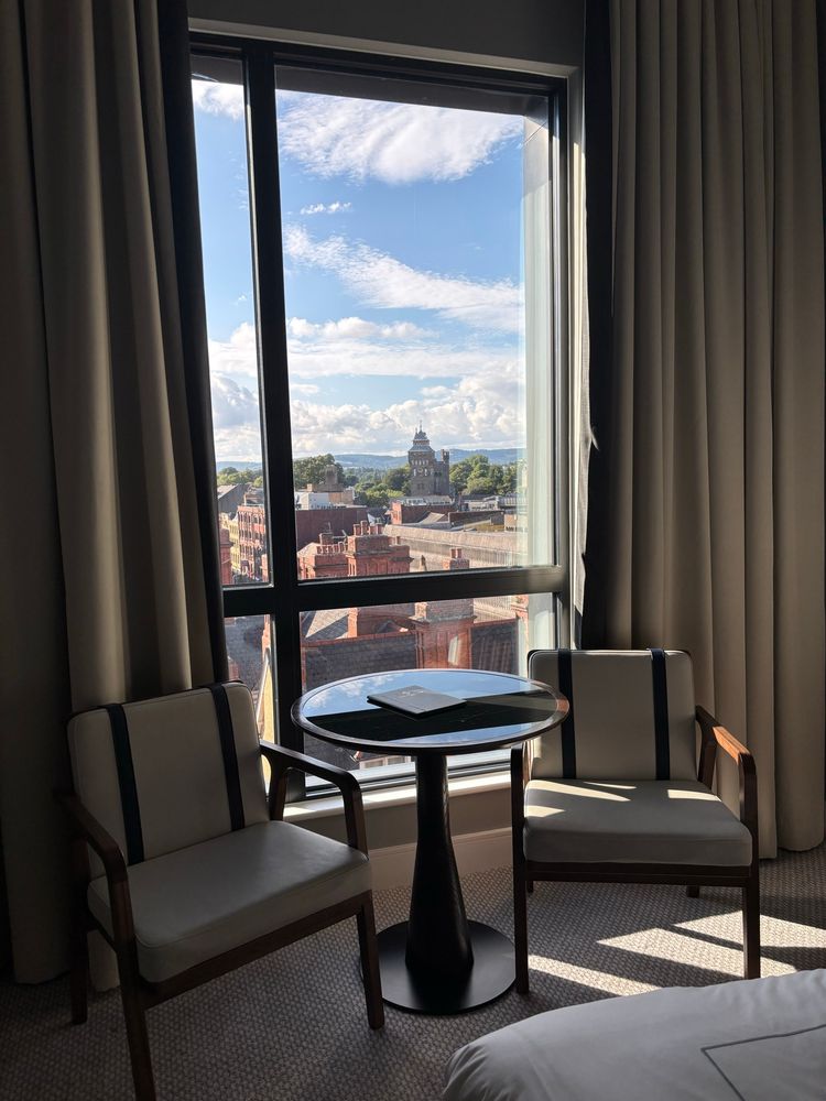 A room looking onto a blue skyline with chairs and table and curtains 