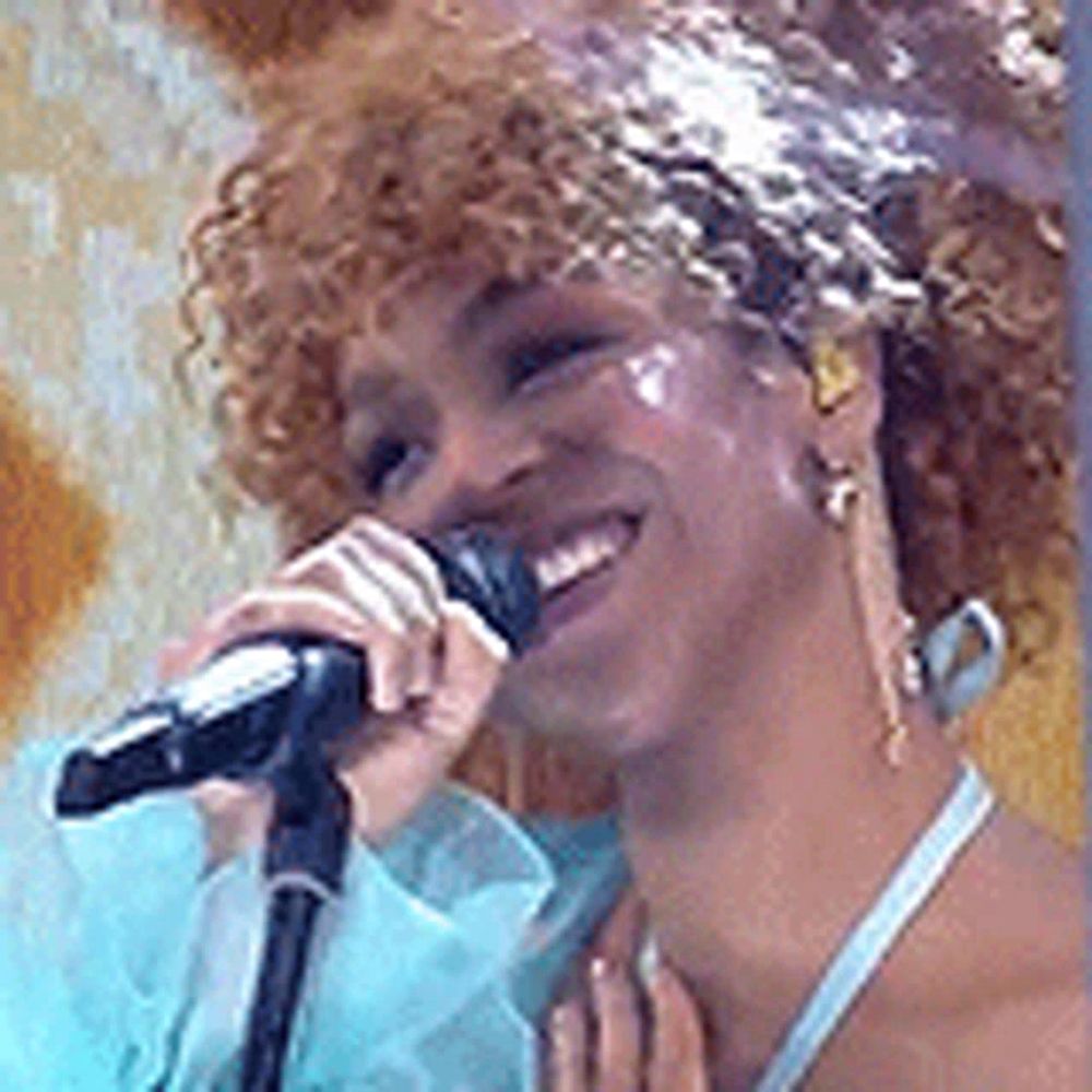 a woman is smiling while singing into a microphone .