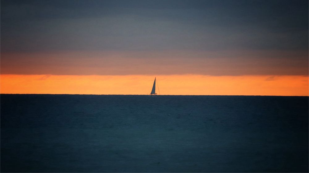 A silhouette of a sail boat on the Pacific Ocean during the sunset. 