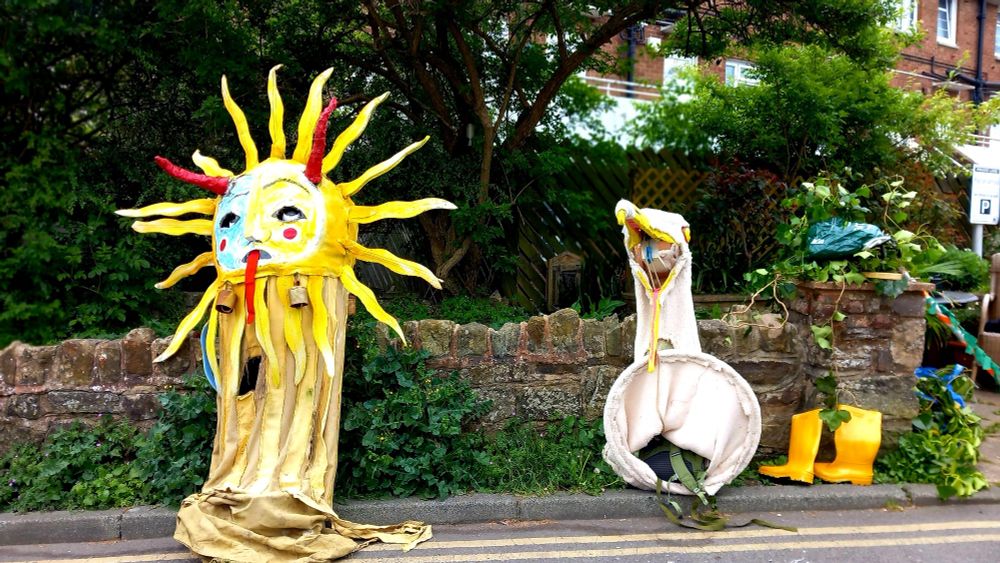 Discarded sun costume and gull costume with wellies by a wall