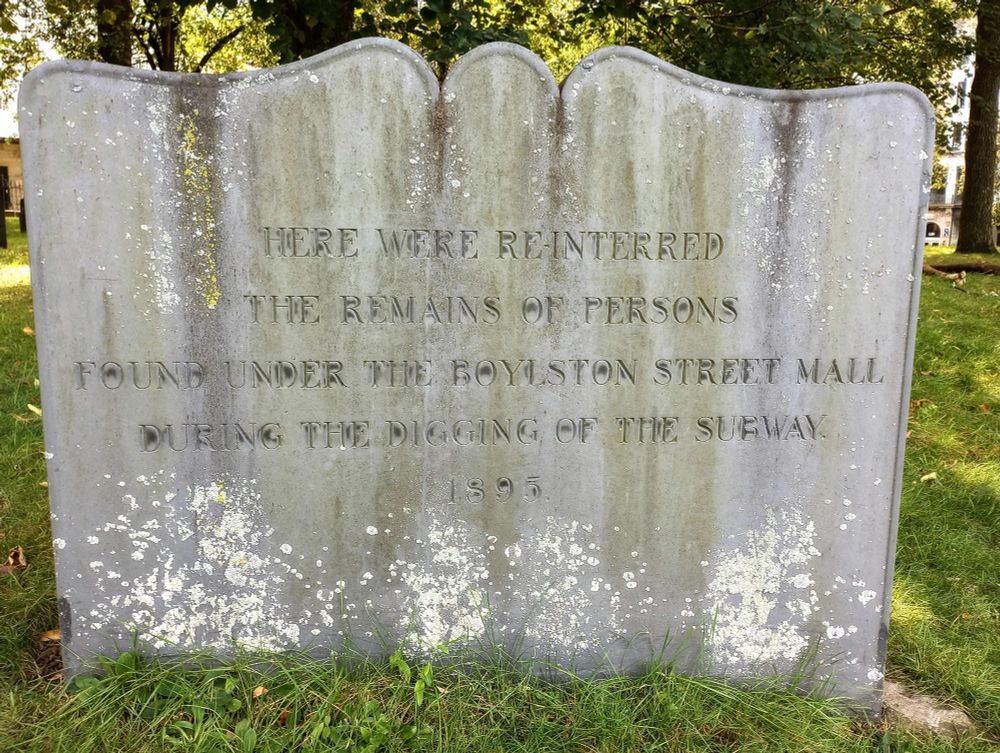 Tombstone that says "Here were re-interred the remains of persons found under the Boylston Street Mall during the digging of the subway 1895"