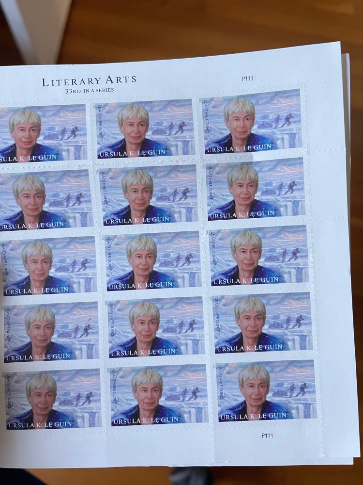 Photo shows a sheet of US postage stamps each printed with an identical portrait of the writer Ursula K LeGuin.