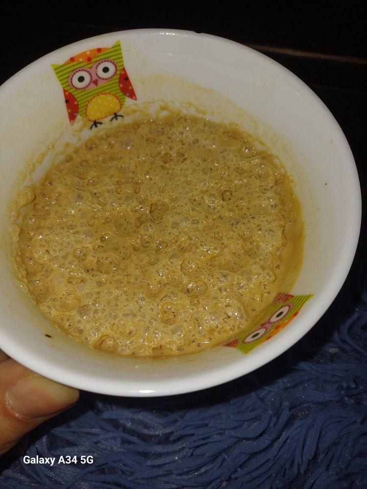 Das innere eines großen Bechers, am Rand eine kleine Eule. Die durch Kaffee bräunliche Hafermilch wirft Blasen, sieht ein bisschen aus Milchreis