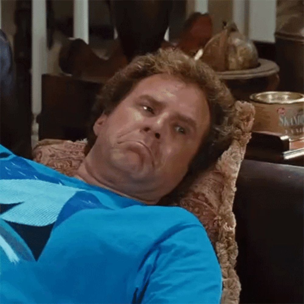 a man is laying on a couch wearing a blue shirt and making a funny face .