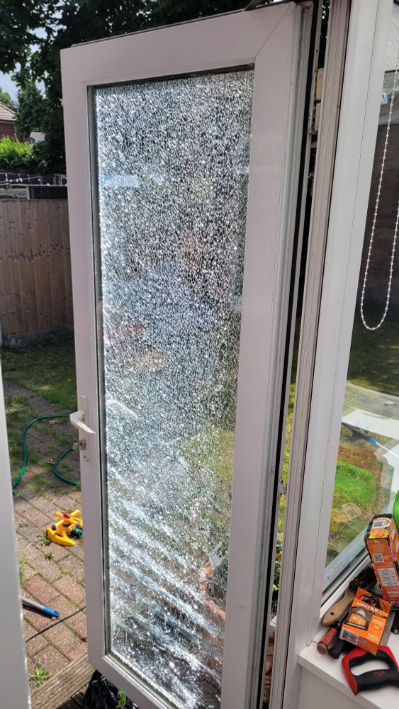 An open glass door to a conservatory. The glass pane has completely fractured throughout. 