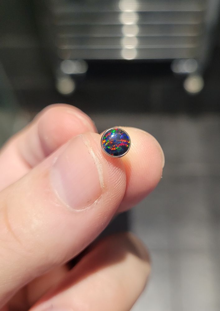Close up picture of a multicoloured, jewel-style, circular earring. 