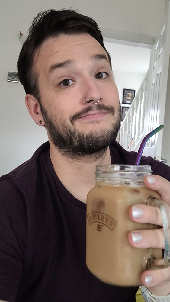A picture of a man holding an iced coffee in a mason jar glass