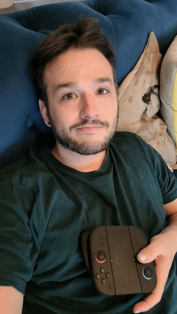 A selfie of me lying on the sofa, looking at the camera, holding a Switch2 controller 