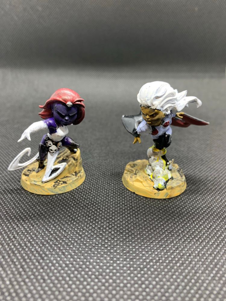 Painted minis of Storm and Mystique from Marvel United XMen game