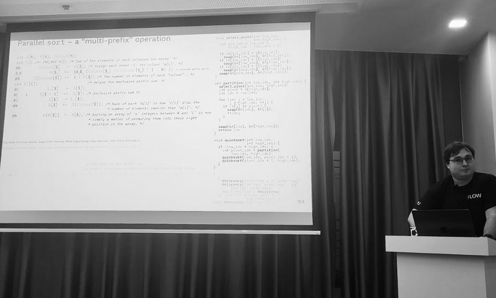 Flow Computing’s Richárd Szalay presenting at the Hungarian C++ Meetup in Budapest. The projected slide shows C++ code titled “Parallel sort, a multi-prefix operation,” illustrating a practical example of parallel-first programming concepts. The image captures Flow’s focus on bridging deep compiler research with real-world software engineering.
