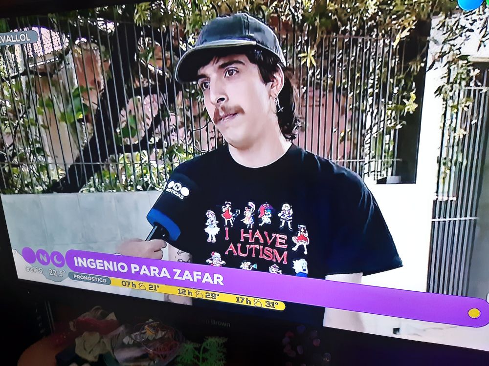 A man giving an interview about how he was almost robbed in the Argentinian TV channel Telefe, wearing a shirt featuring several Touhou Project characters with the text "I HAVE AUTISM".