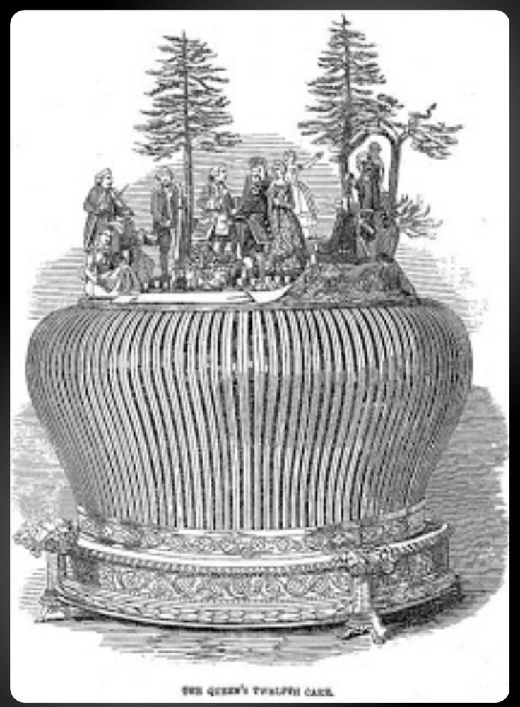 A huge cake with paper frill round the outside and a picnic scene on top