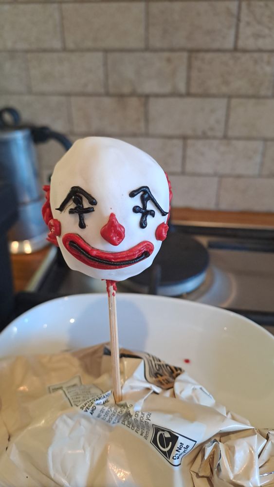 An iced clown head on a stick and a kitchen as a backdrop. Yes, it is terrifying. 